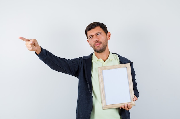 Homem bonito segurando uma moldura em uma roupa casual