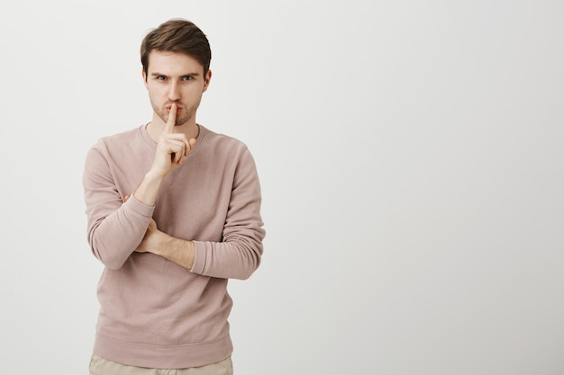 Homem bonito sério diga fique quieto, silencioso, faça um gesto silencioso