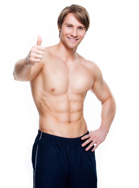 Homem bonito sorridente com torso musculoso mostra sinal de positivo