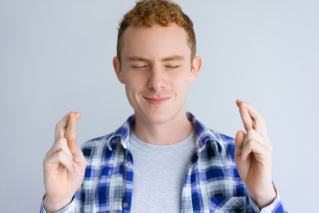 Foto grátis homem bonito sorridente, mostrando o gesto de dedos cruzados