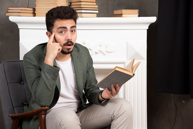 Homem bonito tem uma ideia durante a leitura do livro.