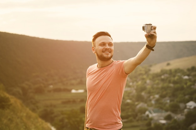 Homem bonito, tirando fotos dele auto com câmera de ação. Filtro instagram vintage retrô