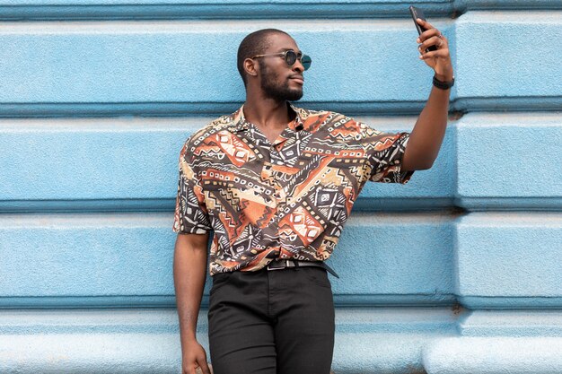 Homem bonito tirando selfie com smartphone moderno ao ar livre