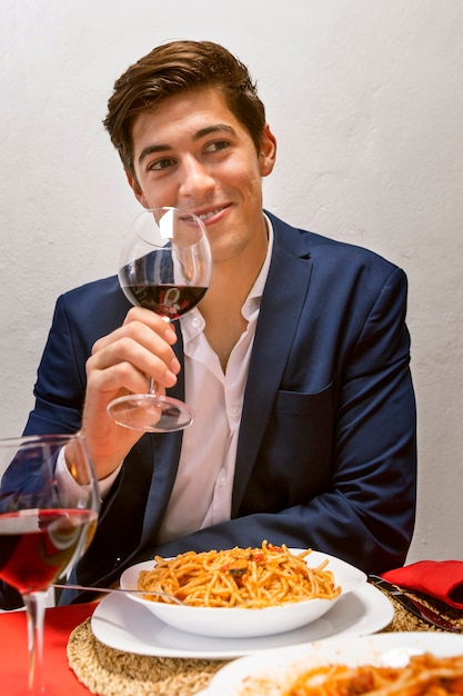 Homem bonito, torcendo com um copo de vinho