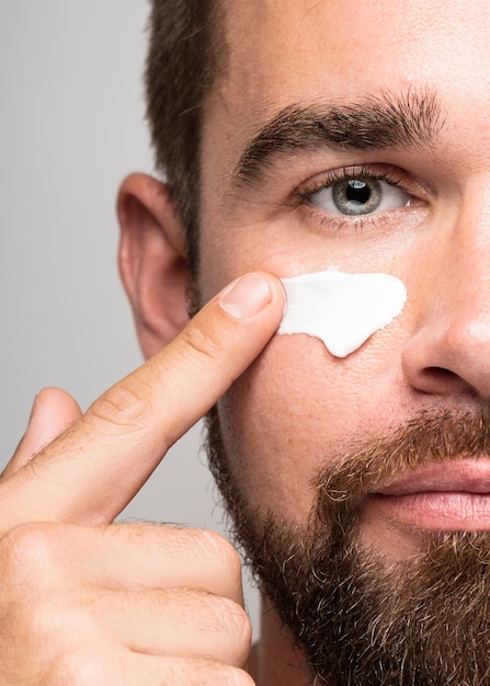 Homem bonito usando creme facial