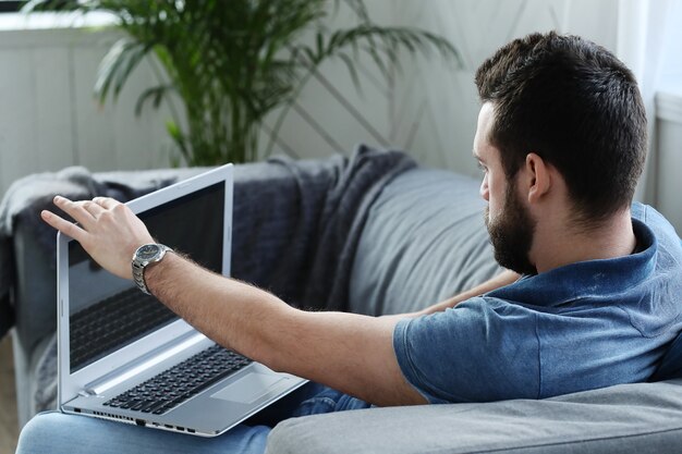 Homem bonito usando o laptop em casa. conceito de teletrabalho