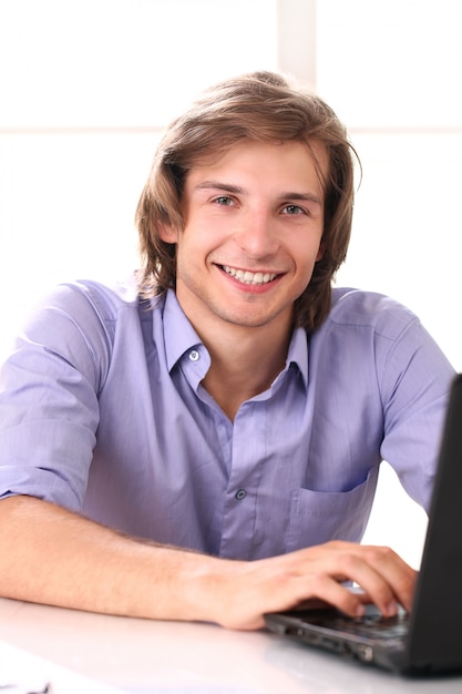 Homem bonito, usando o laptop em seu escritório