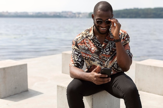 Homem bonito usando smartphone moderno ao ar livre