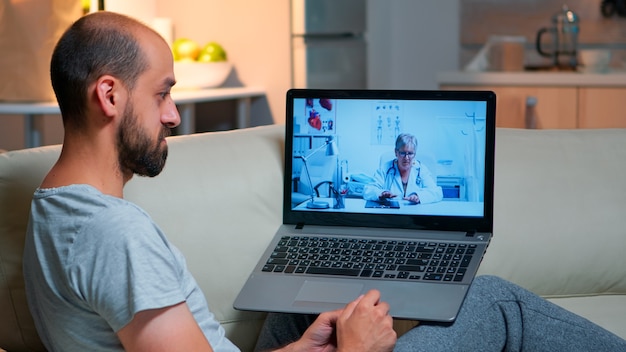 Homem branco conversando com médico durante consulta de telemedicina online