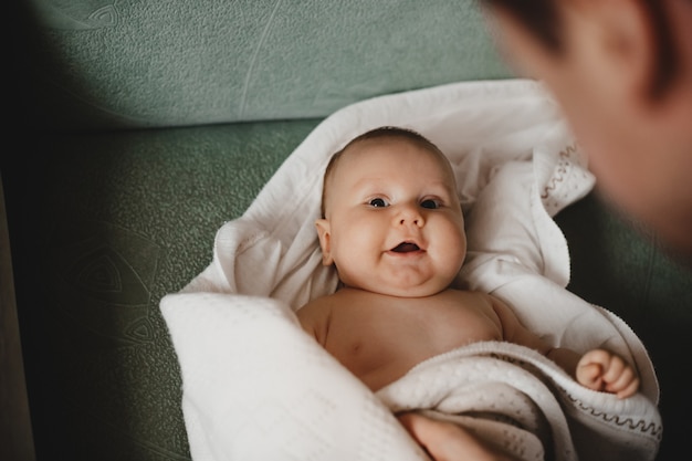 Foto grátis homem brinca com um pequeno bebê recém-nascido envolto em cobertor macio