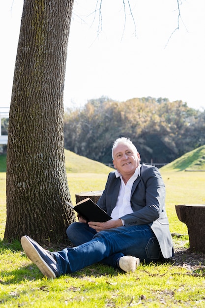 Foto grátis homem calmo que lê ao ar livre