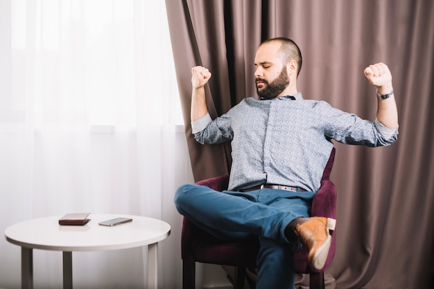 Homem cansado esticando na cadeira