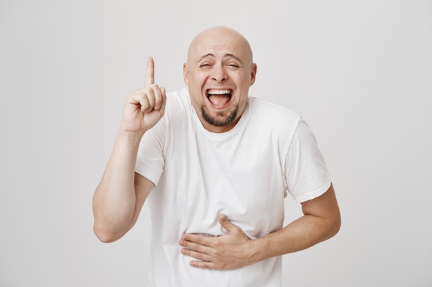 Homem careca de meia-idade feliz rindo, apontando para cima como uma risada