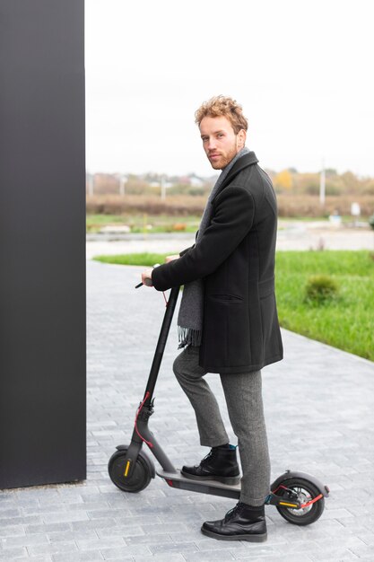 Homem casual posando com uma scooter elétrica