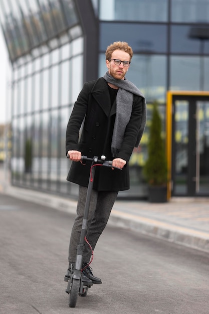 Homem casual posando com uma scooter elétrica