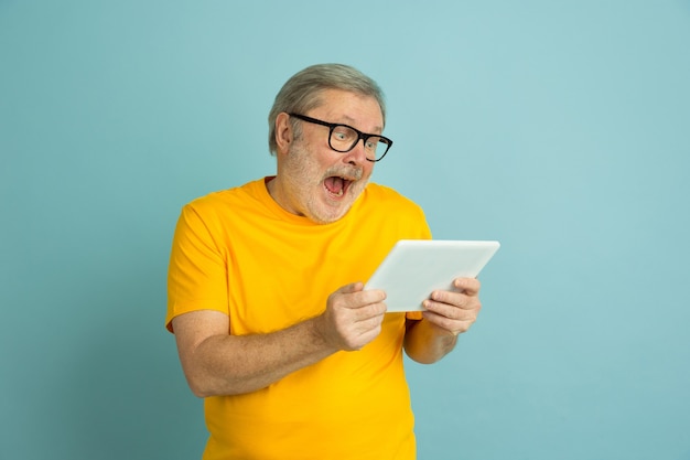 Homem caucasiano atônito usando tablet isolado em azul