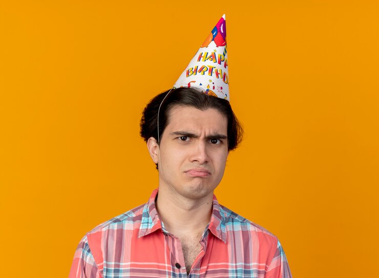Foto grátis homem caucasiano bonito e insatisfeito com boné de aniversário olhando para a câmera