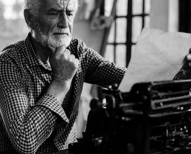 Homem caucasiano sênior, usando a escala de cinza de máquina de escrever vintage