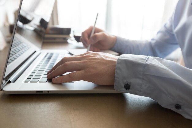 Homem caucasiano usando laptop na mesa