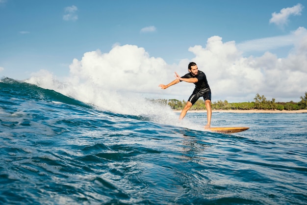 Homem cavalgando sua prancha de surfe e se divertindo, tiro longo