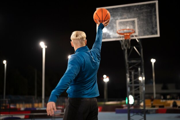 Homem cheio de tiro jogando basquete à noite