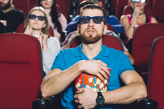 Homem chocado vendo filme no cinema