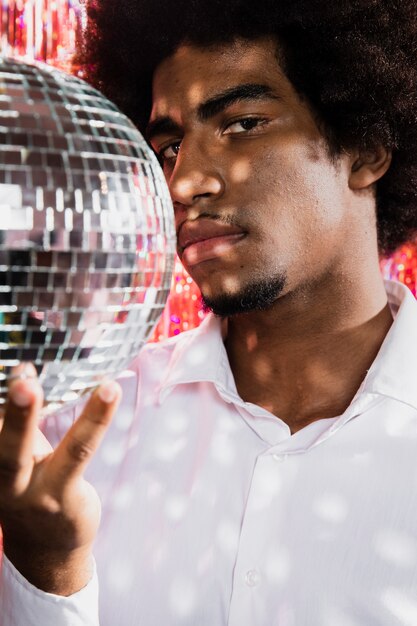 Homem close-up, segurando uma bola de discoteca