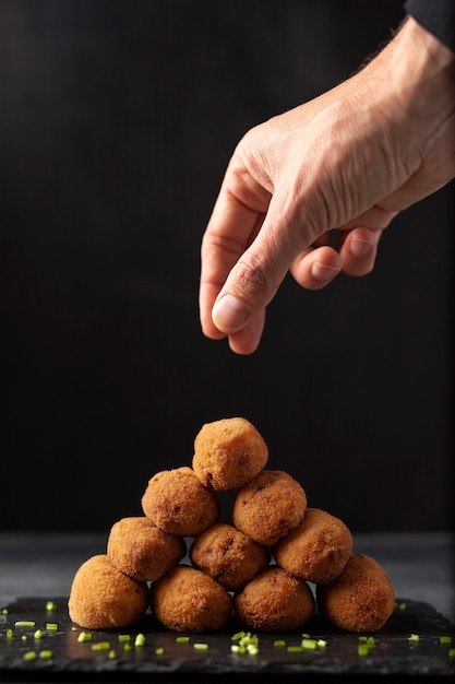 Homem colocando sal em croquetes com salsa