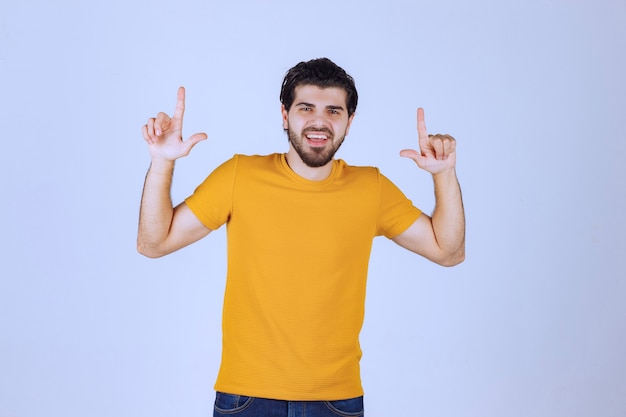 Homem com barba apontando para algo atrás