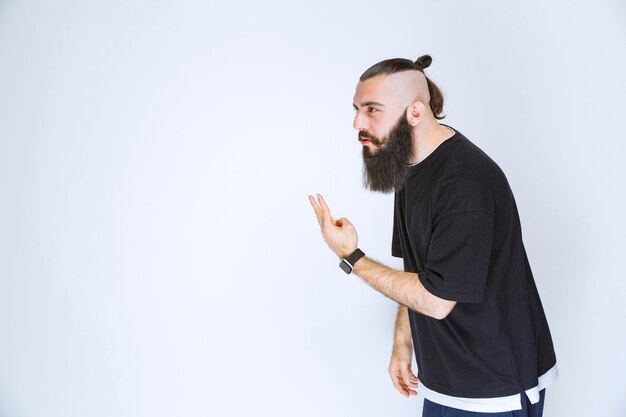 Homem com barba apontando para alguém por perto.