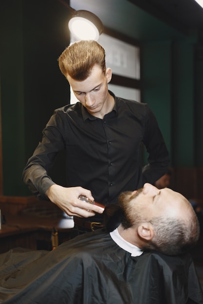 Homem com barba. cabeleireiro com um cliente. homem com uma escova.