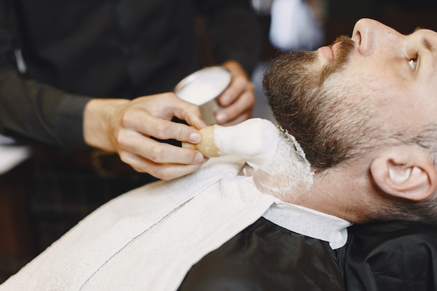 Homem com barba. Cabeleireiro com um cliente. Homem com uma escova.