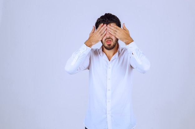 Homem com barba cobrindo os olhos porque está com sono.