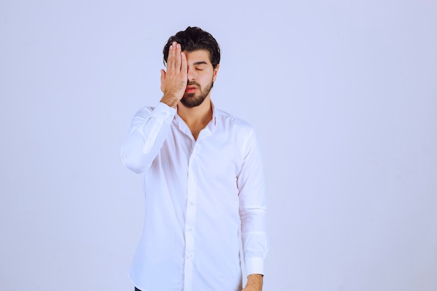 Homem com barba cobrindo os olhos porque está com sono.