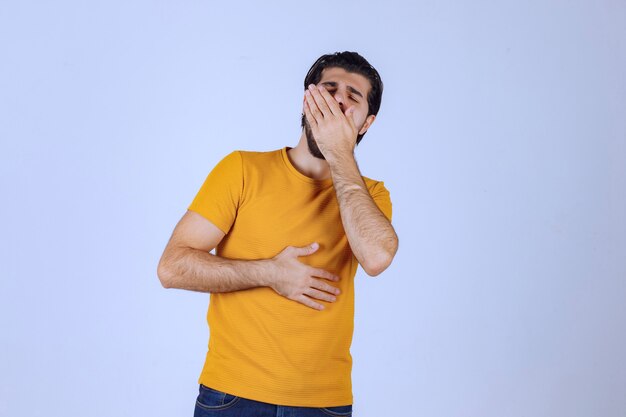 Homem com barba cobrindo os olhos porque está com sono