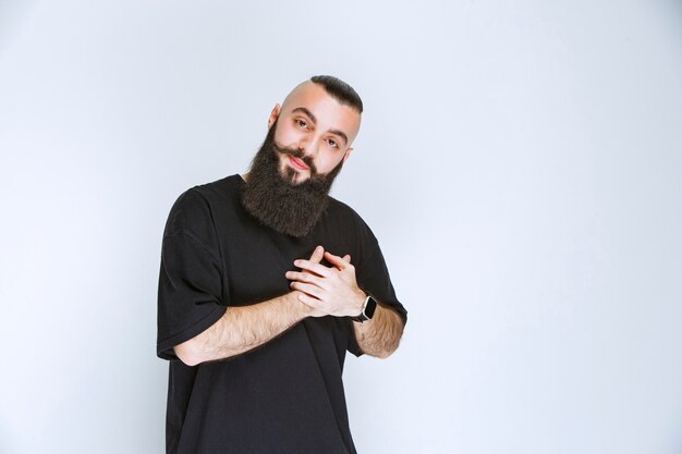 Homem com barba, colocando a mão no coração.