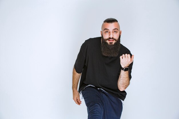 Homem com barba dançando ou fazendo poses extraordinárias.