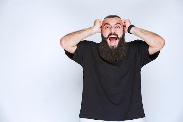 Foto grátis homem com barba fica confuso por causa de algo inesperado.