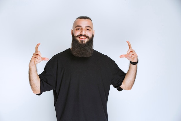 Foto grátis homem com barba, mostrando as dimensões de um objeto.