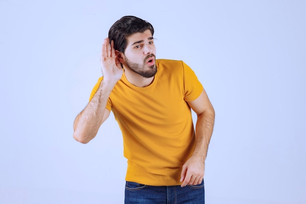 Homem com barba mostrando sua audição e tentando ouvir com atenção