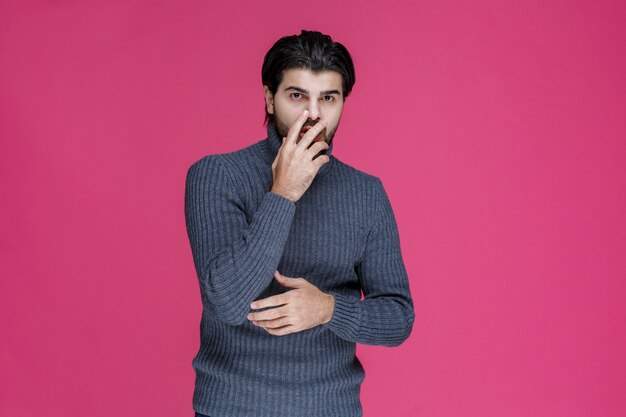 Homem com barba preta parece exausto e entediado.