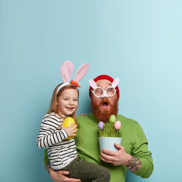 Foto grátis homem com barba ruiva vestindo roupas coloridas e segurando a filha