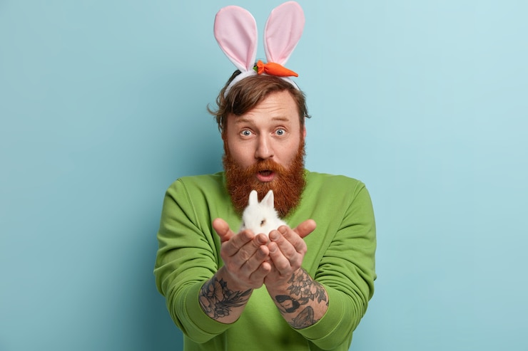 Foto grátis homem com barba ruiva, vestindo roupas coloridas e segurando um coelho
