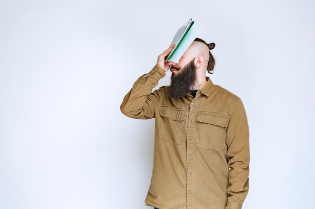 Homem com barba segurando um papel de teste e parece confuso e pensativo.