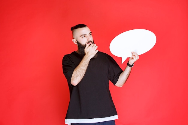 Foto grátis homem com barba segurando um thinkboard oval e brainstorming.