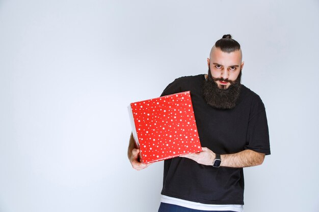 Homem com barba segurando uma caixa de presente vermelha