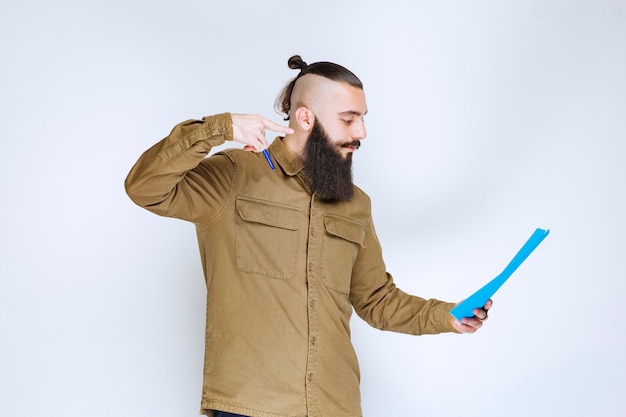 Foto grátis homem com barba verificando a lista de projetos e marcando notas ou correções.