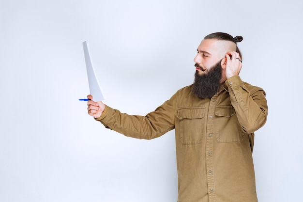 Homem com barba verificando a lista de projetos e marcando notas ou correções.