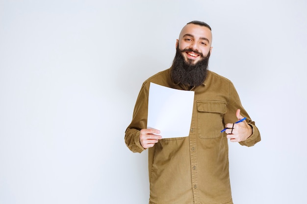 Foto grátis homem com barba verificando a lista de projetos e parece satisfeito.