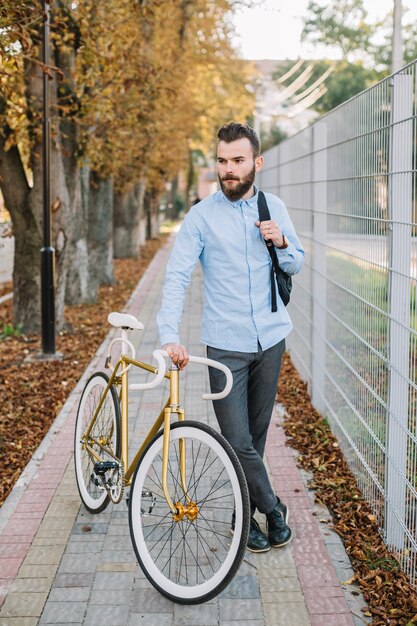 Homem com bicicleta perto da cerca